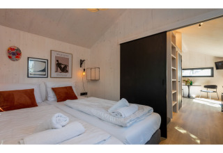 Moderne slaapkamer in Tinyhouse La Mouette met twee bedden, kunst aan de muur en uitzicht op leefruimte.