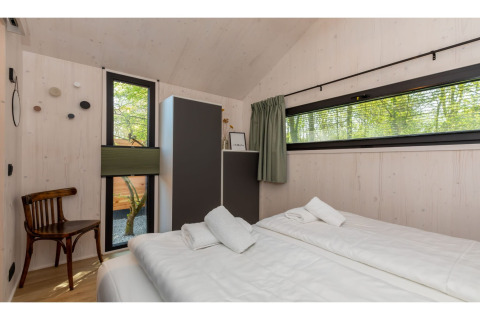 Heldere slaapkamer in Tinyhouse «La Mouette» in Nederland met dubbel bed, kast en raam met uitzicht.