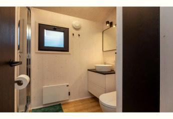Salle de bain moderne dans la tinyhouse « La Mouette » aux Pays-Bas, avec lavabo, miroir et fenêtre.