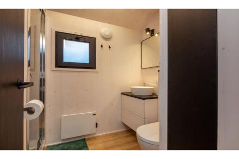 Modern badkamer in tinyhouse 'La Mouette' in Nederland, wastafel, spiegel en klein raam aanwezig.