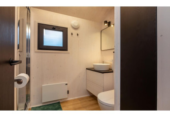 Salle de bain moderne dans la tinyhouse « La Mouette » aux Pays-Bas, avec lavabo, miroir et fenêtre.