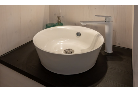 Moderne, ronde waskom met witte kraan op zwart blad in Tinyhouse «La Mouette», Nederland.