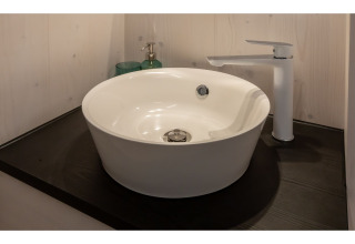 Moderne, ronde waskom met witte kraan op zwart blad in Tinyhouse «La Mouette», Nederland.
