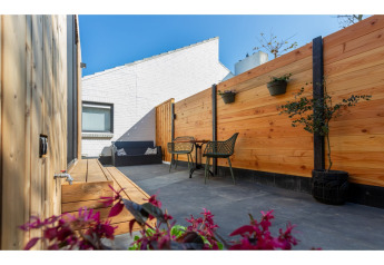 Terrasse accueillante au Tinyhouse La Mouette aux Pays-Bas, avec clôture en bois, assises et plantes en pots.