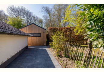 Allée et tiny house en bois, Tinyhouse «La Mouette», entourée de haies et d’arbres aux Pays-Bas.