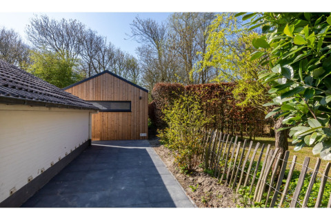 Oprit en houten tiny house, Tinyhouse «La Mouette», omgeven door hagen en bomen in Nederland.