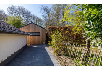 Allée et tiny house en bois, Tinyhouse «La Mouette», entourée de haies et d’arbres aux Pays-Bas.
