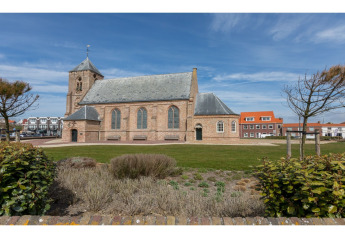 Vue sur une église historique et des maisons modernes depuis le jardin du Tinyhouse «La Mouette» aux Pays-Bas.