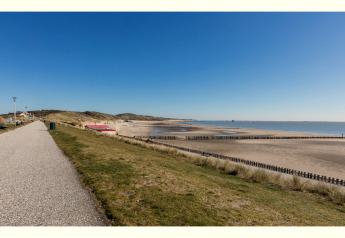 Vue sur la plage et la mer près du Tinyhouse «La Mouette» aux Pays-Bas, sous un ciel bleu clair.