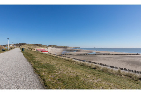 Uitzicht op strand en zee bij Tinyhouse «La Mouette» in Nederland met een helderblauwe lucht.