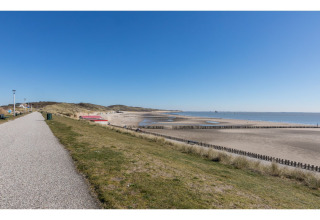 Uitzicht op strand en zee bij Tinyhouse «La Mouette» in Nederland met een helderblauwe lucht.