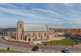 Kerk met toren en huizen errond, gezien vanaf Tinyhouse «La Mouette» in Nederland op een zonnige dag.