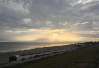 Coucher de soleil à la plage vu de la Tinyhouse «La Mouette» aux Pays-Bas, cabines et ciel nuageux.