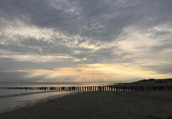 Plage au coucher de soleil avec nuages et brise-lames, vue depuis Tinyhouse «La Mouette» aux Pays-Bas.