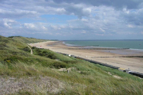 Uitzicht van aan Tinyhouse «La Mouette» in Nederland met duinen, strand en bewolkte hemel erboven.
