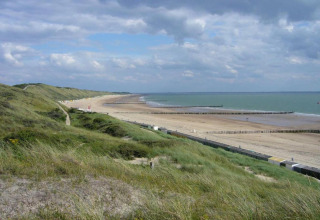 Uitzicht van aan Tinyhouse «La Mouette» in Nederland met duinen, strand en bewolkte hemel erboven.