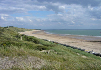 Vue depuis le Tinyhouse «La Mouette» aux Pays-Bas, dunes, plage de sable et ciel nuageux en arrière-plan.