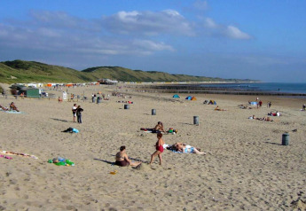 Scène de plage près du Tinyhouse «La Mouette» aux Pays-Bas avec des gens et des dunes verdoyantes.