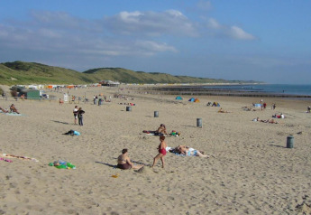 Scène de plage près du Tinyhouse «La Mouette» aux Pays-Bas avec des gens et des dunes verdoyantes.