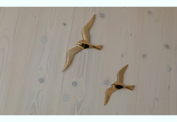Deux oiseaux muraux dorés sur un mur en bois clair dans le Tinyhouse «La Mouette» aux Pays-Bas.