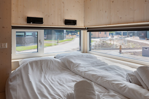 Chambre douillette avec grandes fenêtres dans la tiny house «Noordzee» Résidence De Banjaard 22, aux Pays-Bas.