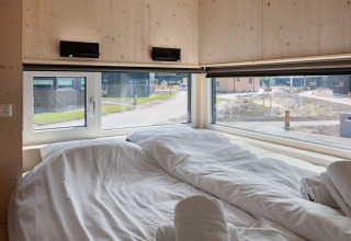 Cozy bedroom with large windows in tiny house ‘Noordzee’ Résidence De Banjaard 22, Netherlands.
