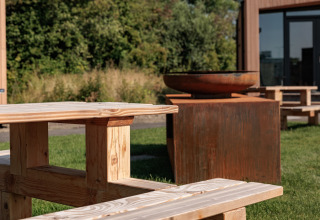 Outdoor wooden bench and fire bowl at tiny house Noordzee, Résidence De Banjaard 22, Netherlands.