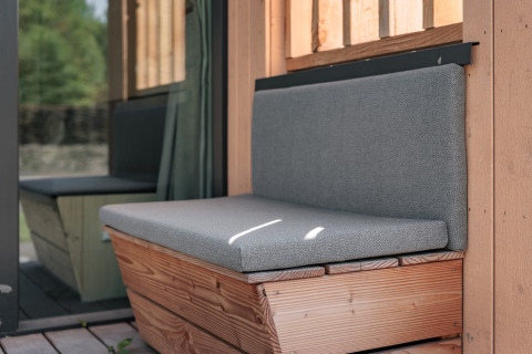Outdoor bench with grey cushions at a tiny house, Noordzee, Résidence De Banjaard 22 in the Netherlands.