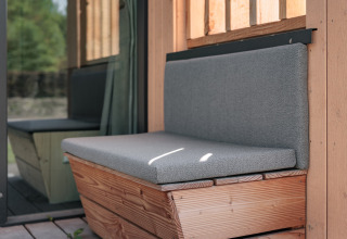 Outdoor bench with grey cushions at a tiny house, Noordzee, Résidence De Banjaard 22 in the Netherlands.