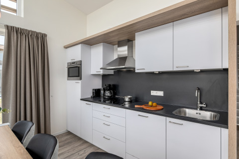 Moderne keuken in de Water Village 4 lodge in Nederland, met witte kasten en zwarte werkblad.