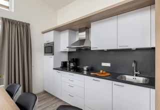 Moderne keuken in de Water Village 4 lodge in Nederland, met witte kasten en zwarte werkblad.