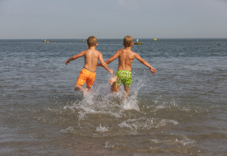 Two children run into the sea at the beach near the tiny house 'Noordzee' Résidence De Banjaard 22 in the Netherlands.