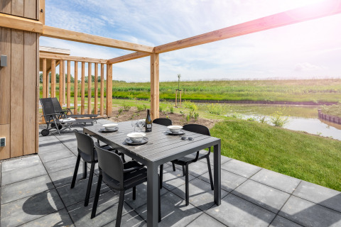 Buitenterras met eettafel en stoelen bij lodge Water Village 4 in Nederland, uitzicht op water en natuur.