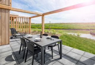 Buitenterras met eettafel en stoelen bij lodge Water Village 4 in Nederland, uitzicht op water en natuur.