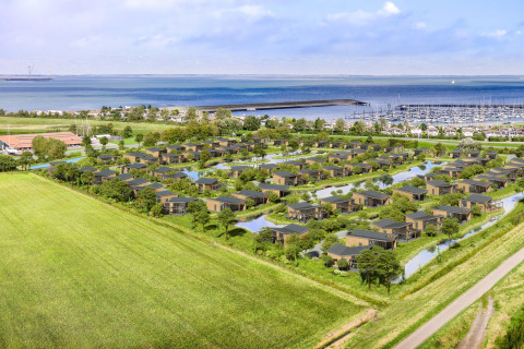 Luchtfoto van Water Village 4 in Nederland met moderne huisjes, waterpartijen en uitzicht op zee.