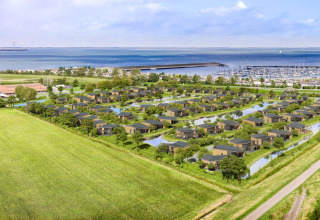 Luchtfoto van Water Village 4 in Nederland met moderne huisjes, waterpartijen en uitzicht op zee.