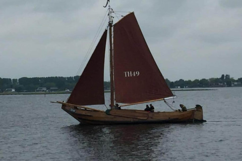 Wooden sailboat with brown sails sailing near Noordzee, Résidence De Banjaard 22 in the Netherlands.