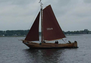 Wooden sailboat with brown sails sailing near Noordzee, Résidence De Banjaard 22 in the Netherlands.