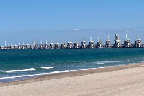 View of the sea and impressive storm surge barrier as seen from the beach at tiny house 'Noordzee' in NL.