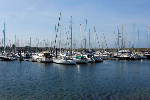 Boten aangemeerd in een jachthaven bij kalm water en blauwe lucht, vlakbij een lodge.