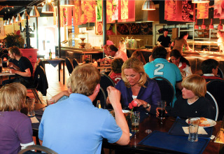 Gezinnen dineren samen in een lodge-restaurant met buffet op de achtergrond en een ontspannen sfeer.