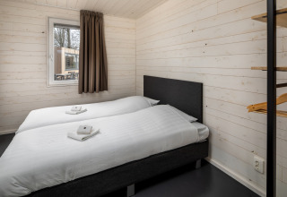 Moderne slaapkamer met twee eenpersoonsbedden en witte wanden in Holiday Park «Schaijk 3» in Nederland.