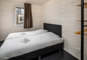 Chambre moderne avec deux lits simples et murs blancs au Holiday Park «Schaijk 3» aux Pays-Bas.