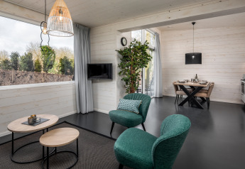 Salon moderne d'une tiny house au Holiday Park Schaijk 3 aux Pays-Bas avec sièges verts et coin repas.