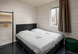 Moderne soveværelse med to enkeltsenge, trævægge og vindue i Holiday Park «Schaijk 3», Holland.