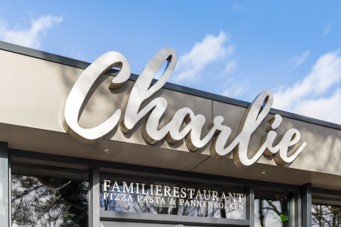 Entrance to Charlie family restaurant with a large sign, offering pizza, pasta and pancakes specialties.