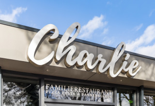 Entrée du restaurant familial Charlie avec une grande enseigne, proposant pizzas, pâtes et crêpes.
