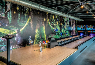 Bowling lane in a tiny house with a magical forest mural on the wall and colorful pins at the end.