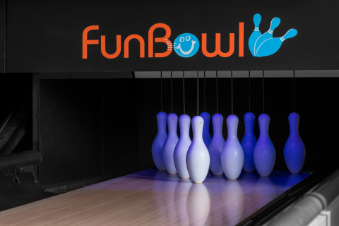 Bowlingkegler oplyst med blå lys under FunBowl-skilt, bowlingbane med neon-tema interiør.