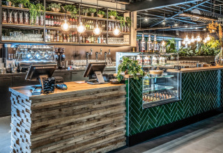 Moderne Bar im Tiny House mit grünen Pflanzen, Flaschenregalen und stilvoller Holz- und Glastheke.